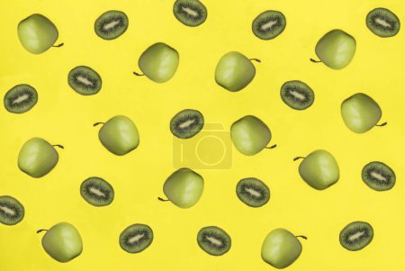 Photo for Green apple and kiwi on the yellow background. Pattern. Flat lay. - Royalty Free Image