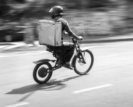 Téléchargez les photos : Motion blur, a courier on a bicycle is in a hurry to deliver an order - en image libre de droit