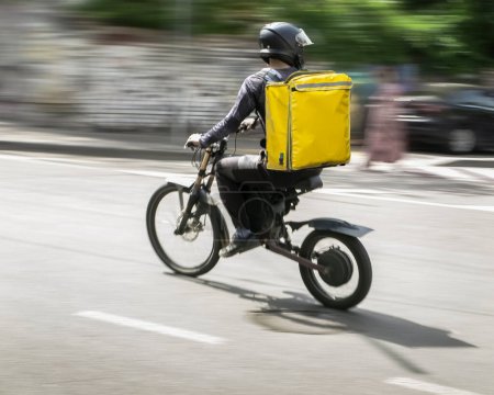 Téléchargez les photos : Motion blur, a courier on a bicycle is in a hurry to deliver an order - en image libre de droit