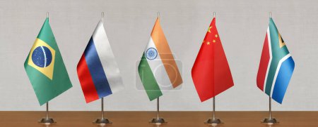 Tischfahnen der BRICS-Staaten auf grauem, verschwommenem Hintergrund