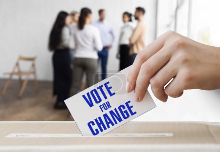 Hand hält einen Stimmzettel und die Einschreibestimme für Veränderung in der Nähe der Box