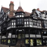 Chester. Cheshire, United Kingdom - 20 March 2024 : Old half timbered buildings on the corner of Eastgate and stairs leading to the upper rows