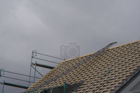Photo for A residential building is being energetically renovated. The roofers have sealed the roof and installed the battens, now the roof tiles can be laid. The threatening gray sky is a synonym for the bad situation in the construction industry - Royalty Free Image