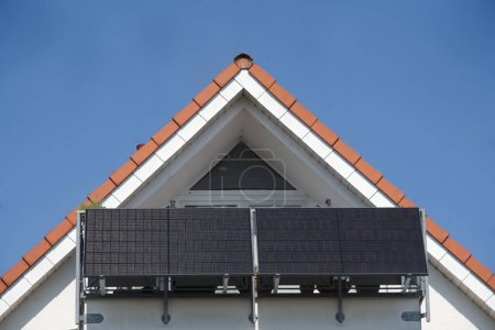 Photo for Balcony power station installed on the railing of a balcony. The apartment directly under the roof with the large balcony is illuminated by the sun. The solar panels will deliver a lot of electricity thanks to the cloudless sky - Royalty Free Image