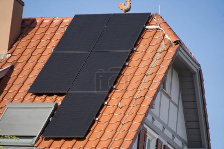 Foto de Módulos solares en el techo de una antigua casa de entramado de madera. Cielos azules claros y hermoso sol garantizan una alta producción de electricidad. - Imagen libre de derechos