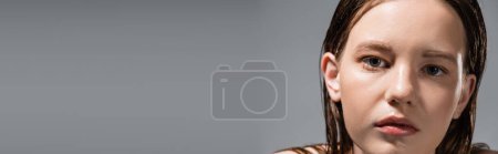 Fair haired woman with wet skin looking at camera isolated on grey, banner 