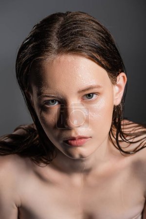 High angle view of model with wet face looking at camera isolated on grey 