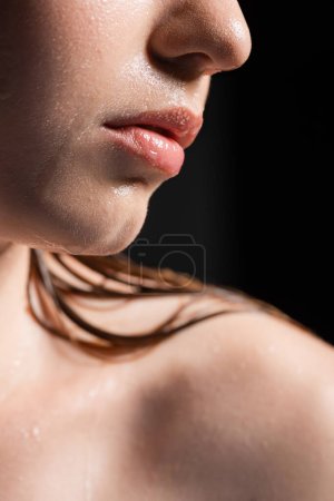 Nahaufnahme von Frau mit nasser Haut und Lippen isoliert auf schwarz