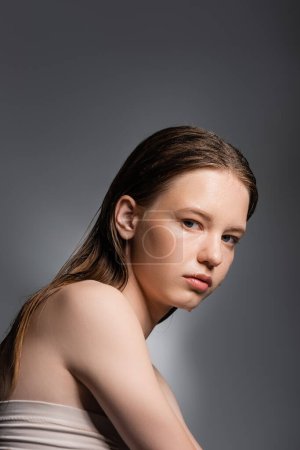 Foto de Mujer joven con agua en la cara mirando a la cámara aislada en gris - Imagen libre de derechos