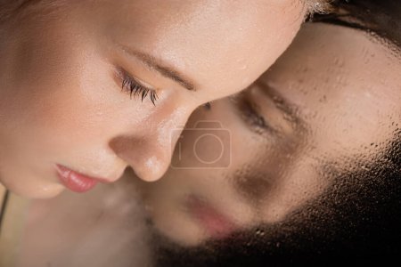 Close up view of young woman with wet skin posing near mirror on black  magic mug #616813540