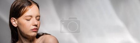 Young woman with water on face and hair standing on abstract grey background, banner 