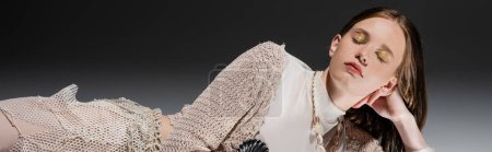 Téléchargez les photos : Sirène avec maquillage doré et jupe résille couchée sur fond gris, bannière - en image libre de droit