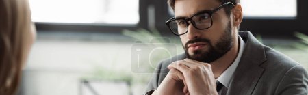 Photo for Businessman in eyeglasses and formal wear looking at blurred candidate on job interview, banner - Royalty Free Image
