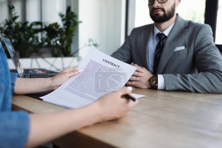 Cropped view of candidate holding contract near blurred manager during job interview 