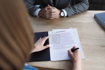 Cropped view of candidate signing contract near businessman during job interview 