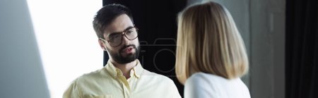 Businessman in eyeglasses talking to blurred intern in office, banner 
