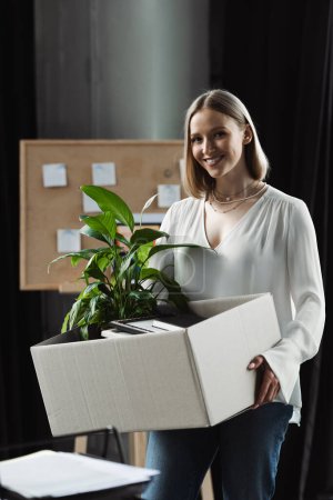 Positive new worker holding carton box with stuff in office 