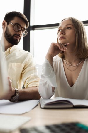 Photo for Pensive intern looking away near notebook and businessman talking in office - Royalty Free Image