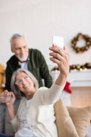 glücklich reife Frau mit Brille Selfie mit Ehemann auf verschwommenem Hintergrund 