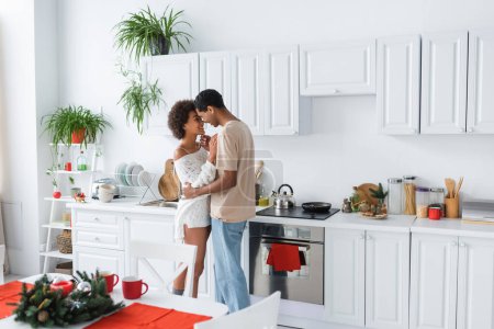 young and sexy african american couple hugging in spacious kitchen with white furniture