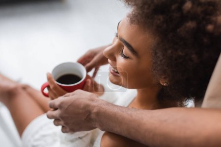 high angle view of man holding cup of coffee near pleased african american woman
