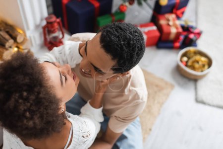 Blick von oben auf glückliches afrikanisch-amerikanisches Paar, das sich am Weihnachtstag zu Hause umarmt