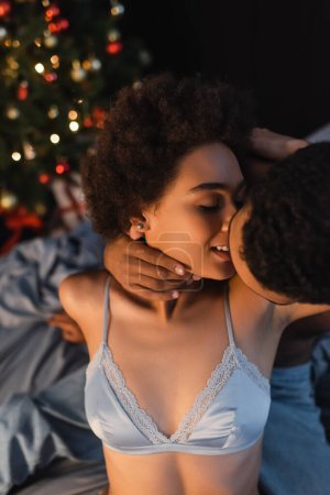 séduisante et souriante femme afro-américaine près de petit ami l'embrasser la veille de Noël