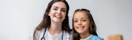Positive doctor and kid looking at camera in hospital ward, banner 