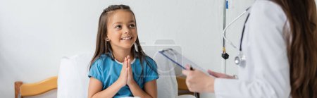 Chica haciendo por favor gesto cerca de pediatra con portapapeles en la clínica, pancarta 
