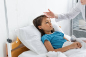 Pediatrician checking temperature of patient in hospital ward  t-shirt #620101302