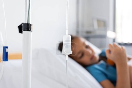 Intravenous therapy on stand near blurred sick child in hospital 