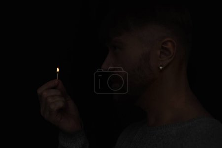Photo for Side view of man holding lit match during energy blackout isolated on black - Royalty Free Image