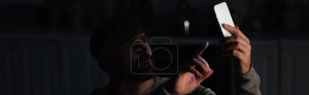 Téléchargez les photos : Homme inquiet pointant vers le smartphone tout en attrapant le signal perdu lors d'une panne de courant, bannière - en image libre de droit