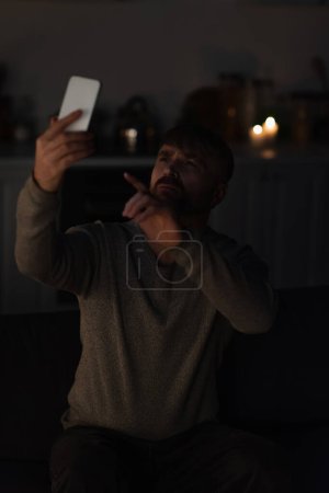 Foto de Hombre apuntando al teléfono móvil mientras captura la señal perdida debido al apagón de energía - Imagen libre de derechos
