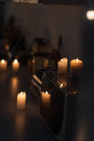 palące się świece na kuchence mikrofalowej i kuchennym stole w ciemności spowodowane wyłączeniem prądu