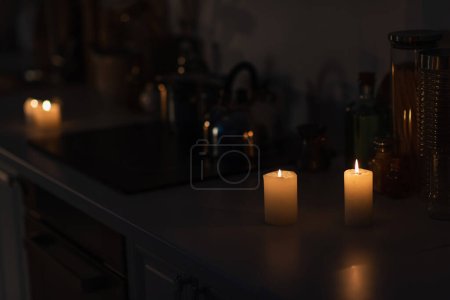 Küchentheke mit Geschirr und brennenden Kerzen bei Stromausfall