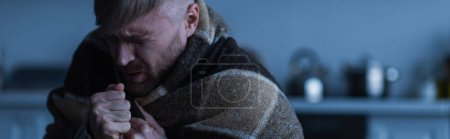 Photo for Stressed man wrapped in warm blanket sitting in twilight with closed eyes, banner - Royalty Free Image