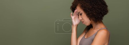Téléchargez les photos : Vue latérale de triste femme afro-américaine en haut debout isolé sur vert, bannière - en image libre de droit
