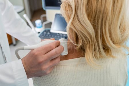 Ausgeschnittene Ansicht des Arztes, der das Lymphsystem der blonden Frau mit Ultraschall untersucht