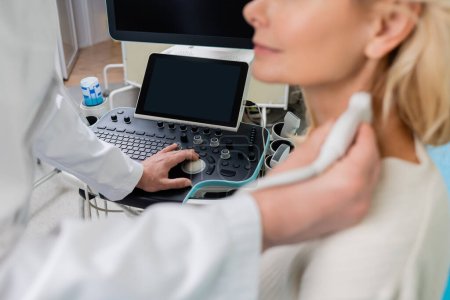 Foto de Vista parcial del médico que examina a la mujer borrosa mientras opera la máquina de ultrasonido - Imagen libre de derechos