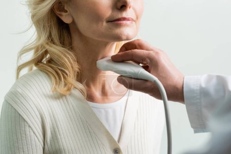 Ausgeschnittene Ansicht einer reifen Frau in der Nähe eines Arztes bei der Ultraschalluntersuchung ihres Kehlkopfes