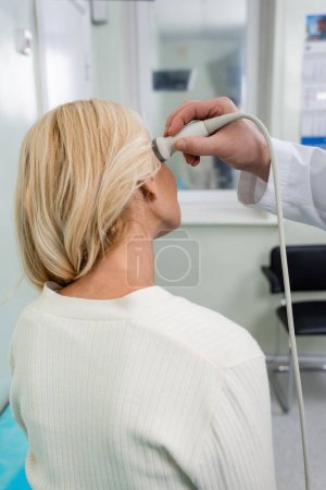 Foto de Vista posterior de la mujer rubia cerca del médico haciendo diagnósticos neurológicos de su cabeza con ultrasonido - Imagen libre de derechos