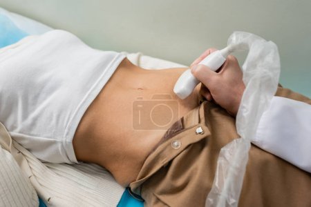 Téléchargez les photos : Vue partielle du médecin faisant une échographie néphrologique de la femme menteuse - en image libre de droit