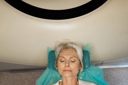 top view of blonde woman making diagnostics on computed tomography scanner in clinic