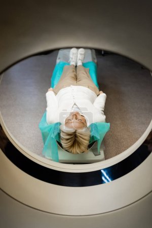 full length view of middle aged woman lying during examination on ct scanner in clinic