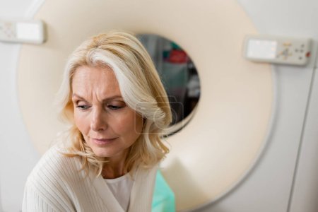 worried middle aged woman near computed tomography machine in clinic