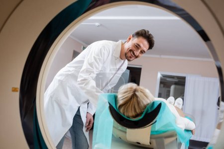 Radiologe lächelt Frau bei Computertomographie im Krankenhaus an