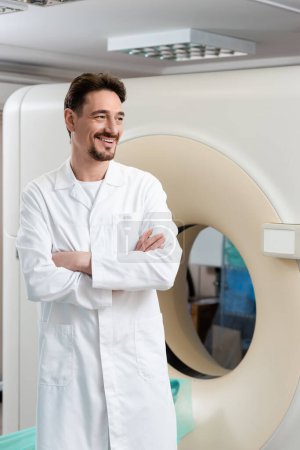 Photo for Smiling radiologist standing near computed tomography scanner and looking away - Royalty Free Image