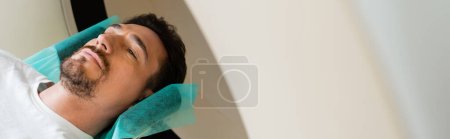Photo for High angle view of bearded adult man doing diagnostics on ct scanner in hospital, banner - Royalty Free Image