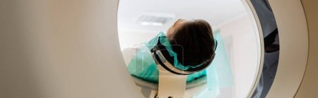 Foto de Adulto morena hombre haciendo diagnósticos en tomografía computarizada escáner en clínica, bandera - Imagen libre de derechos